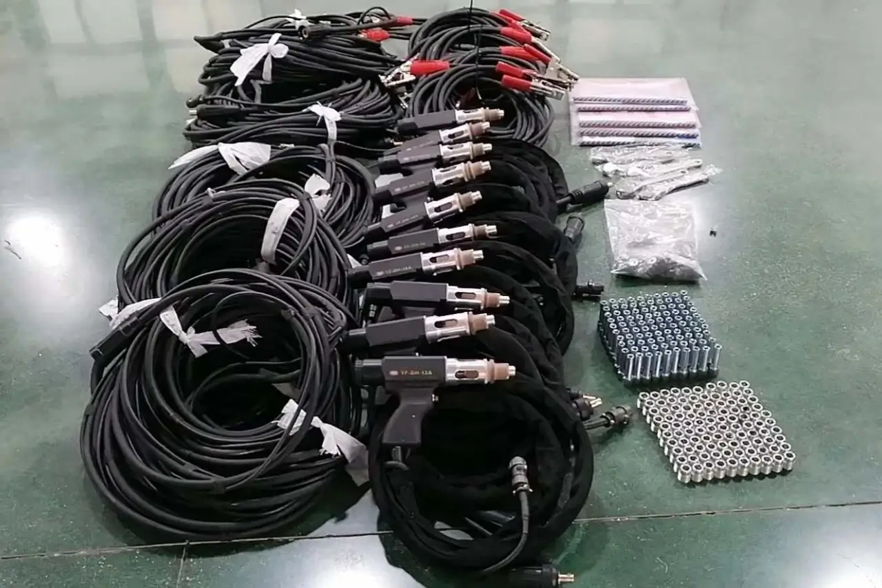 Multiple rows of stud welding guns, coiled cables, and organized boxes of fasteners and accessories laid out for large-scale operations.