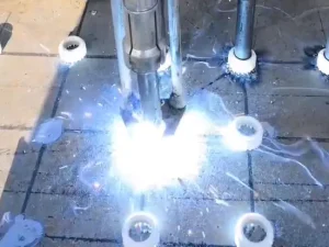 Professional arc stud welding process using ceramic ferrules on a steel plate.