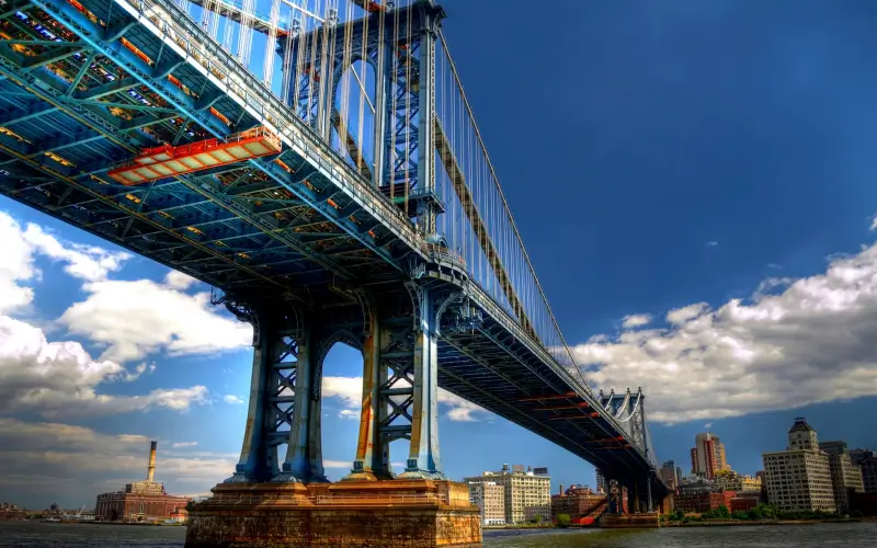 A low-angle majestic view of a large suspension bridge, highlighting the critical role of shear studs in steel-concrete composite bridge structures.