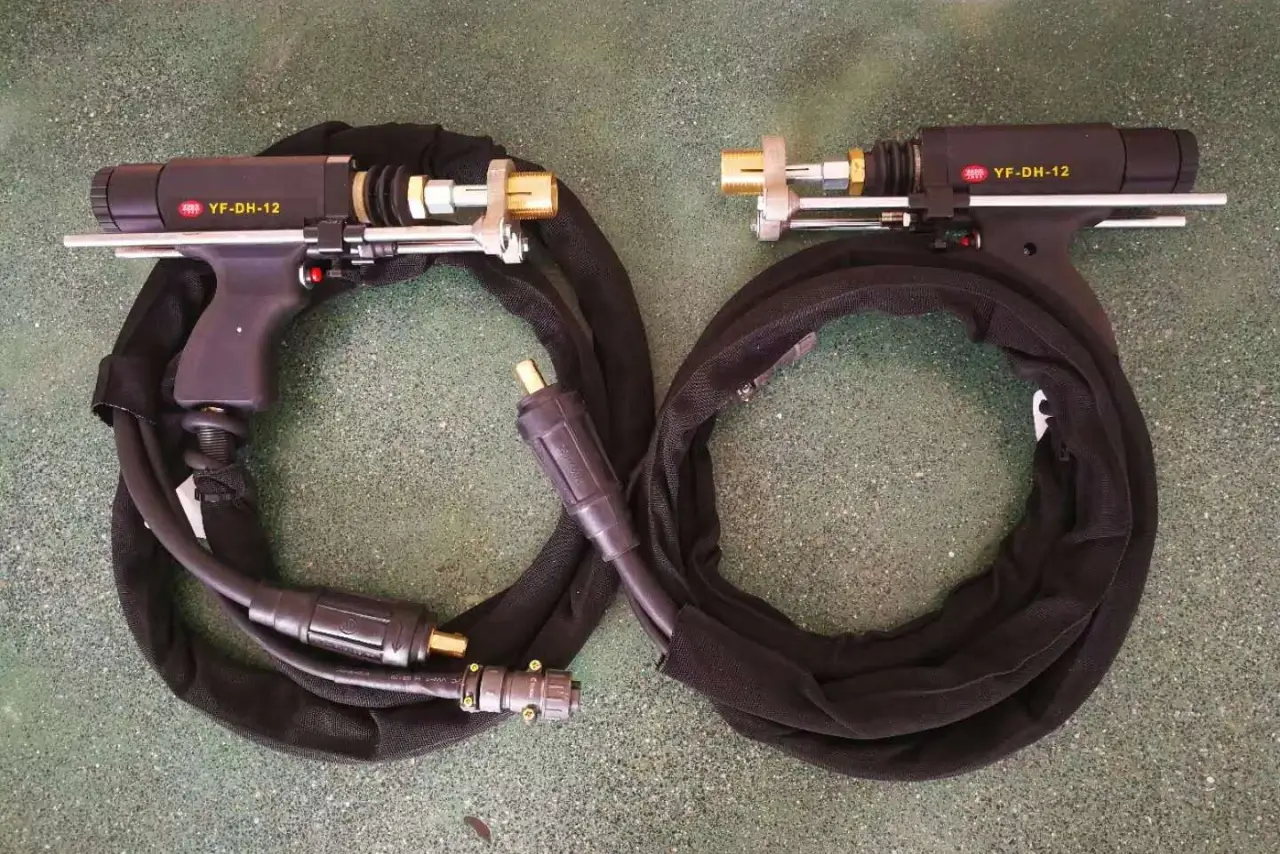 Two professional-grade stud welding guns with integrated cable protection sleeves and adjustable metal stabilizing legs.