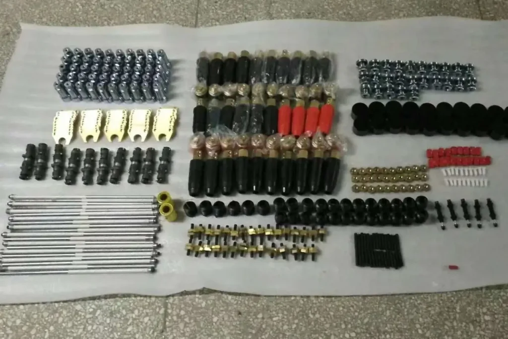 Large-scale inventory of stud welding gun parts including rows of steel chucks, brass adapters, insulated support rods, and cable connectors.