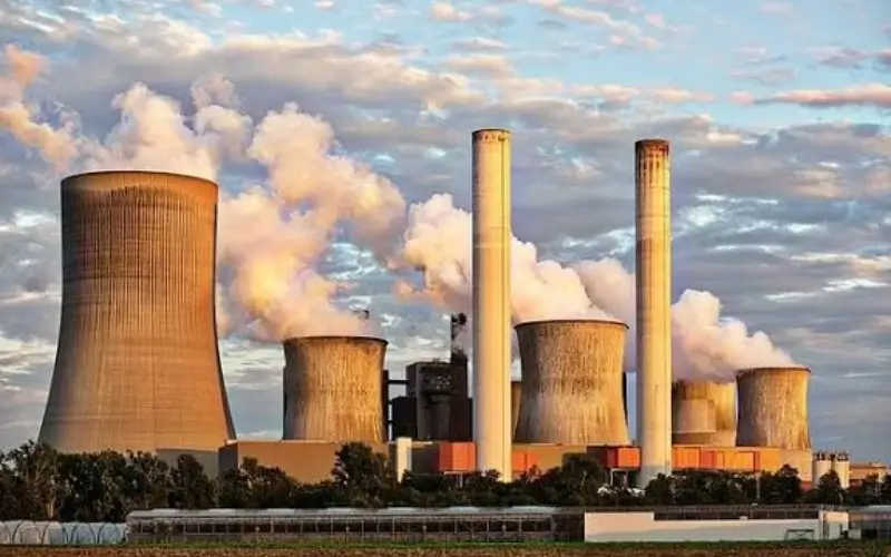 Industrial coal-fired power plant with cooling towers and chimneys emitting steam