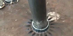 Shear stud welded to steel with remnants of the ceramic ferrule being chipped away.